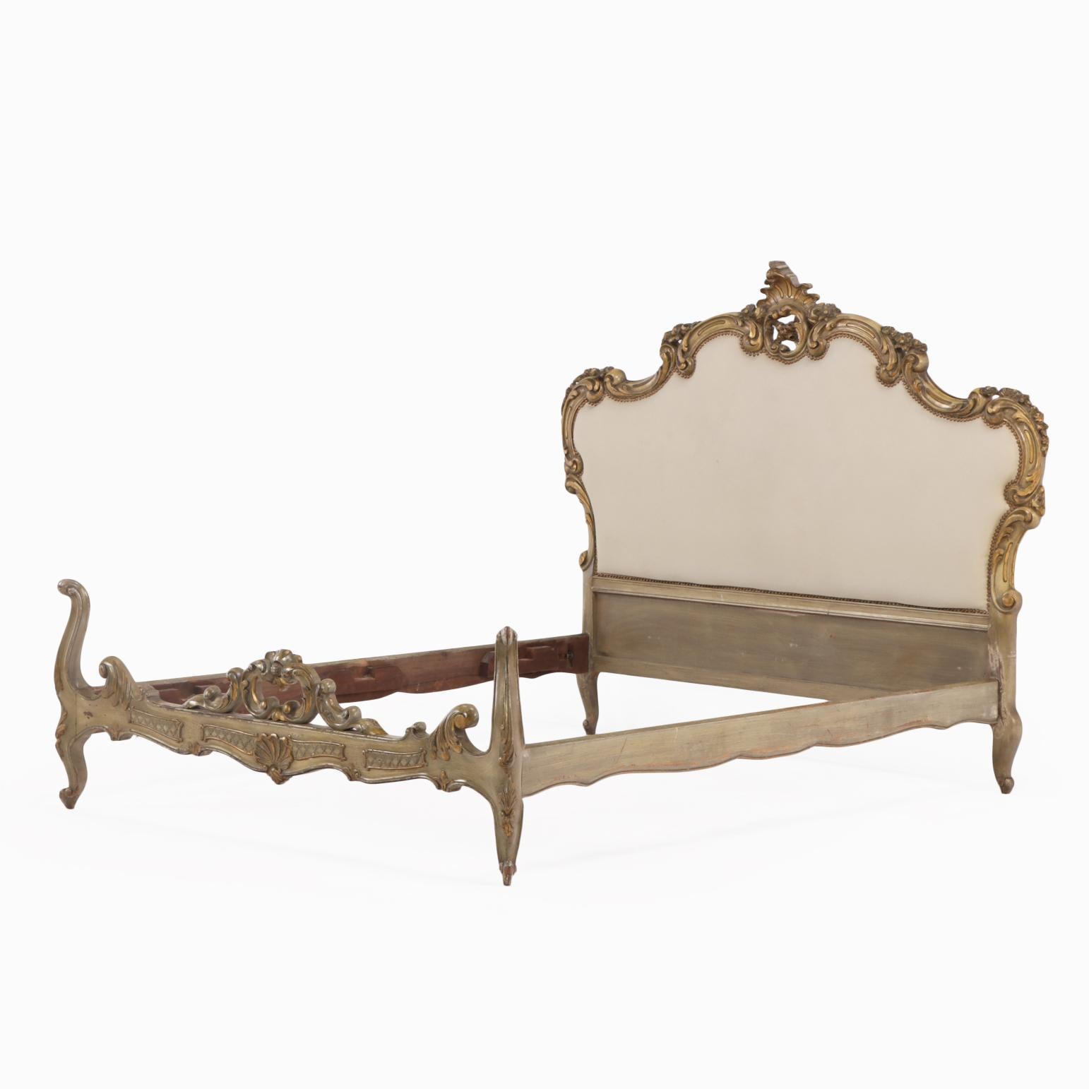 This elegant early 20th-century French Louis XV style bed features a richly carved wooden frame with scrolling rococo motifs and a soft painted finish. The shapely headboard is upholstered in new fabric, offering a fresh, updated look while