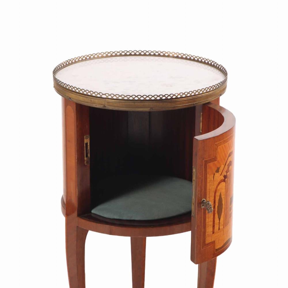 The circular marble top set within a pierced brass gallery, the case and door with inlaid town scene, the door opening to an open interior, raised on slender cabriole legs ending in cast sabots.