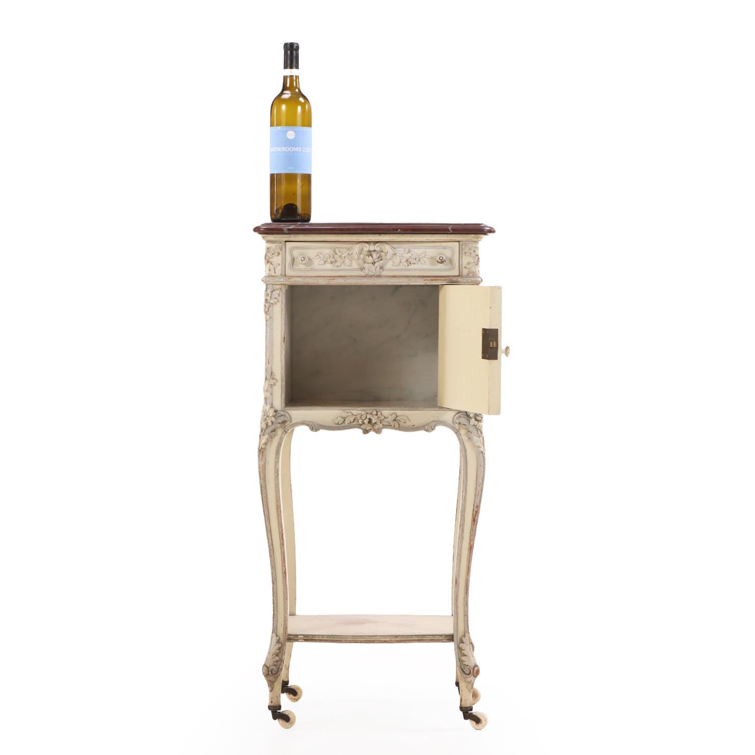 Délicatement proportionnée avec des détails raffinés, cette charmante table de nuit présente un plateau en marbre façonné au-dessus d'un tiroir unique et d'une porte de placard, s'ouvrant sur un intérieur tapissé de marbre. Le coffret repose sur de