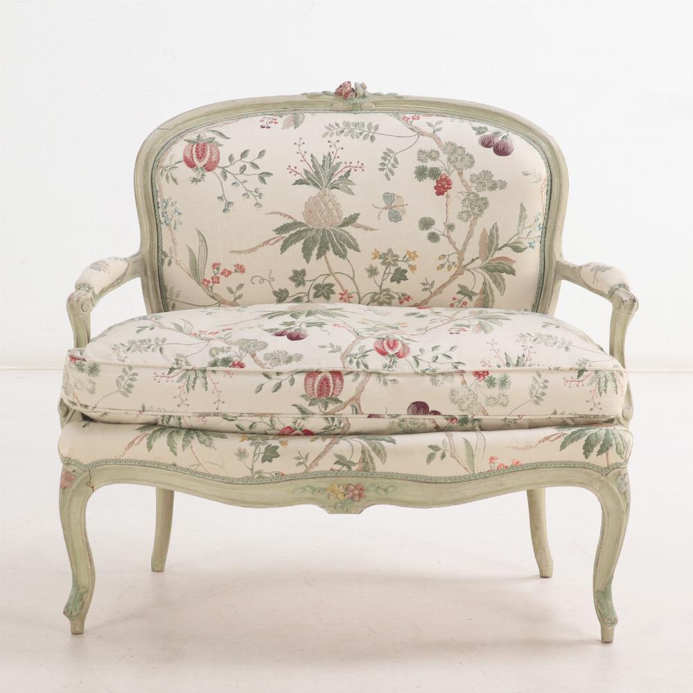 Ce charmant petit canapé de style Louis XV est tapissé d'un somptueux tissu floral sur la structure et le coussin libre, ce qui rend le canapé encore plus douillet. Le cadre est orné de fleurs sculptées et peintes, de feuilles d'acanthe, et soutenu