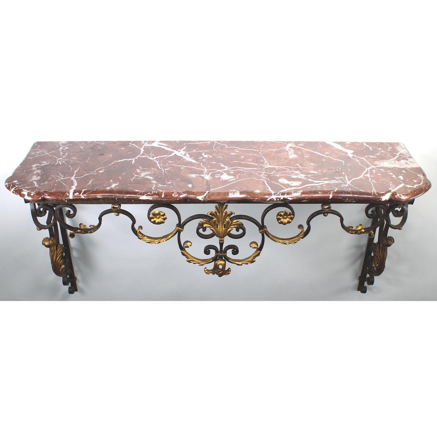 A French Louis XV Style Wrought Iron Wall-Mounting Console with Marble Top. The scrolled slight serpentine wrought iron scrolled frame with its original finish and parcel-gilt acanthus and leaves, fitted with a veined Rouge Royal marble top, circa
