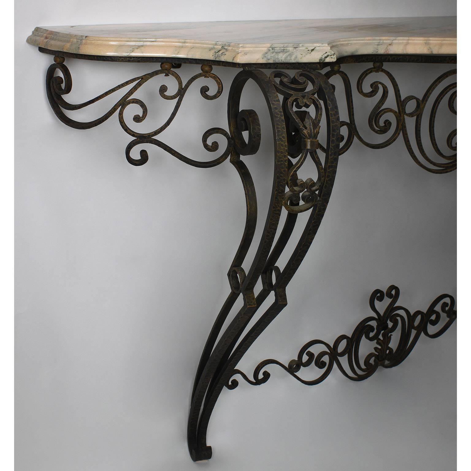 Consola mural francesa de hierro forjado estilo Luis XV con encimera de mármol. El armazón de hierro con forma de serpentina y patas delanteras volutas con pies cónicos, provisto de una encimera de mármol veteado de color rosáceo, hacia el siglo