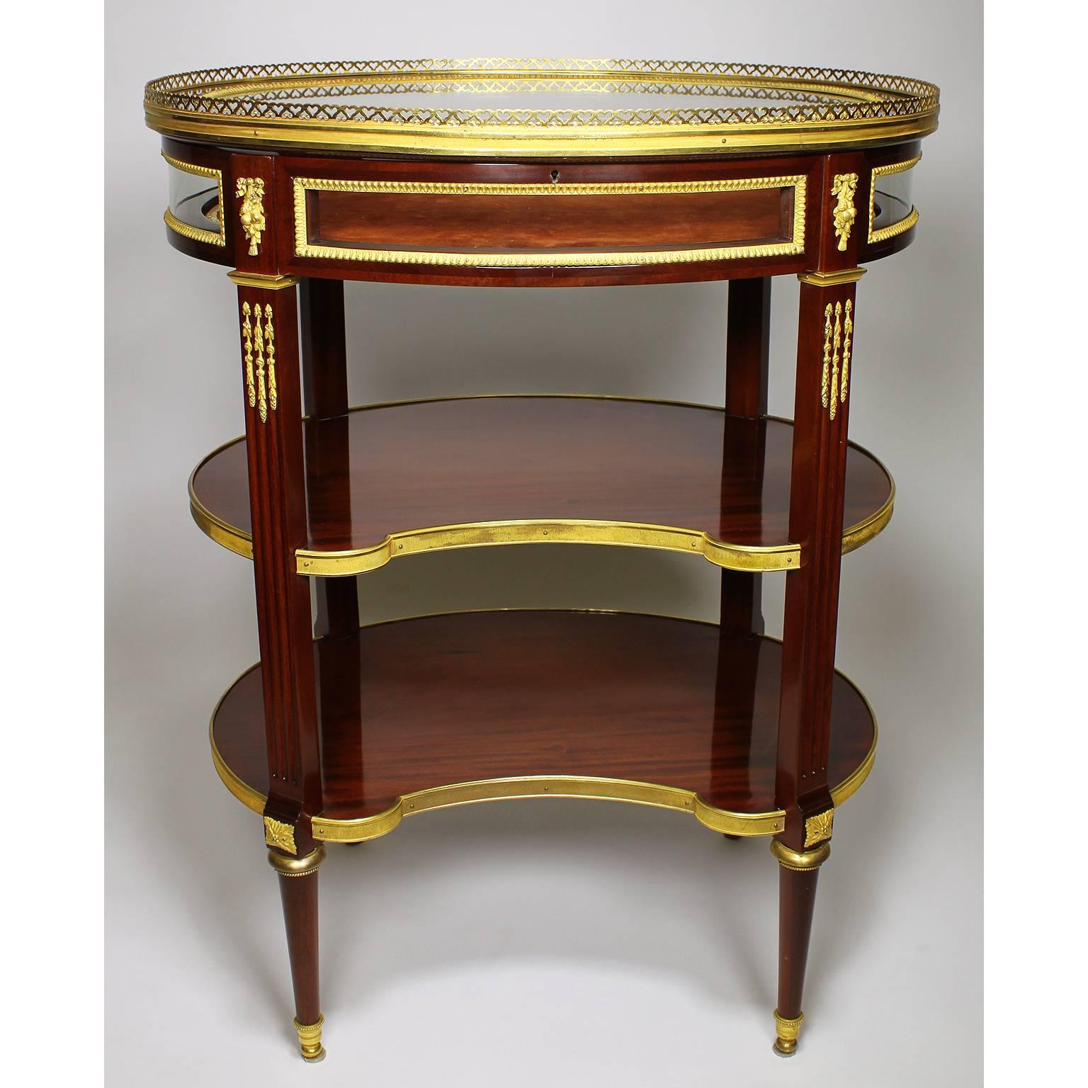 A fine French 19th-20th century Louis XVI style Belle Époque ormolu-mounted mahogany ovoid vitrine table, attributed to François Linke (1855-1946), with a bevelled glass lift top surmounted with a pierced gilt bronze gallery in the shape of hearts
