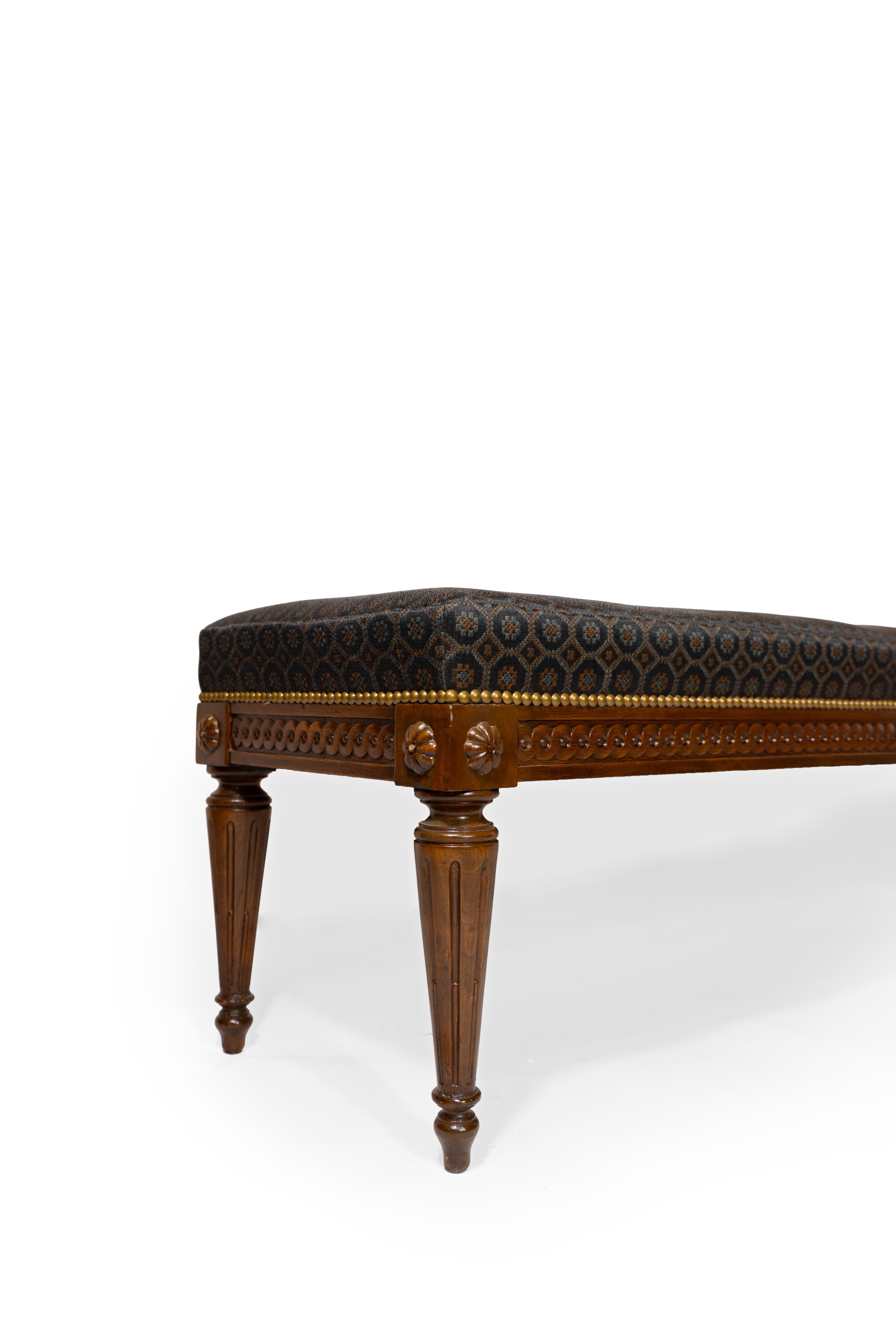 Banco francés de caoba de estilo Luis XVI, con patas redondas acanaladas y ahusadas que sostienen un delantal con motivos geouche. El asiento, recién tapizado, está revestido de crin de caballo negra con sutiles rosetones de color azul y cobre