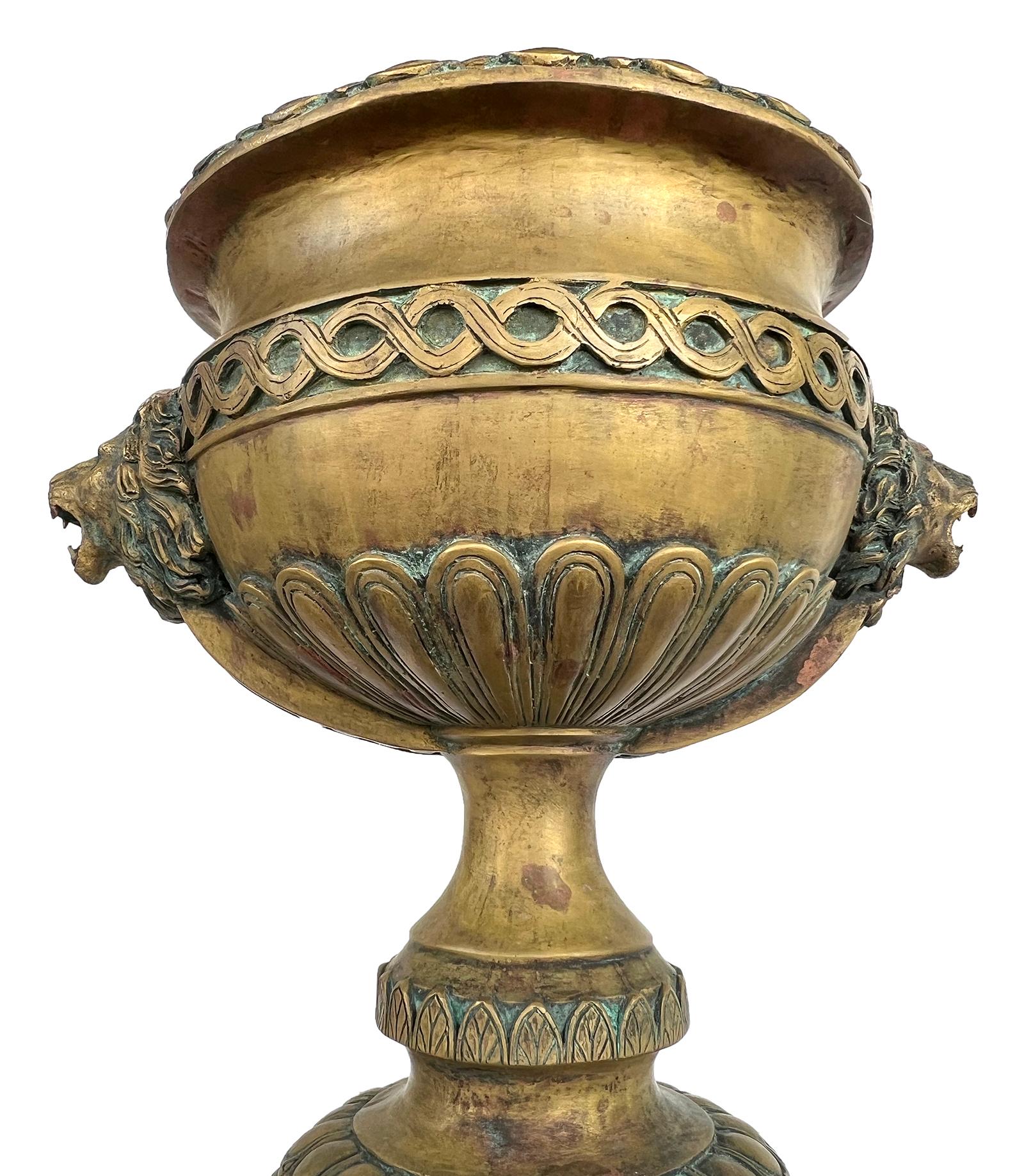 Of large scale and solid construction, the footed urn flanked by lion head handles and cast with guilloche and egg-and-dart bands.