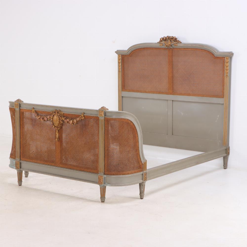 A French Louis XVI style carved, painted and giltwood full size bed C 1900. The neutral gray frame with beautifully carved floral details embellished in gold, caned headboard and curved footboard.  Interior Dimensions 55.75