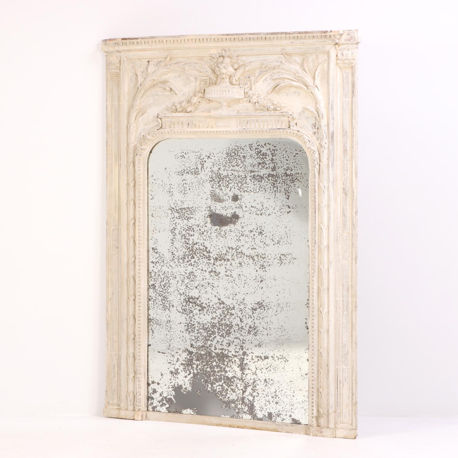 Questo bellissimo specchio di grandi dimensioni in legno intagliato e gesso presenta dettagli classici ed è dipinto con una morbida finitura bianca. Lo specchio, con un piano ad angolo arrotondato, è incorniciato da ampi lati con colonne e