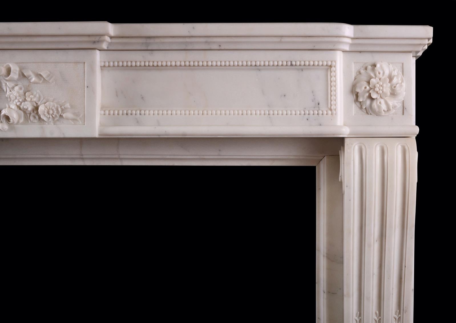 A good quality French Louis XVI style fireplace in Statuary white marble. The shaped jambs with fluting carved with husks, surmounted by rosette paterae. The bowed frieze with fine carved beading and central panel with flowers and ribbons. Moulded