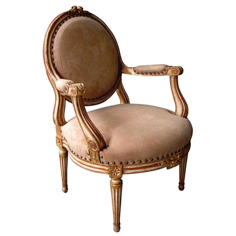 A French Louis XVI Style Ivory Painted and Parcel Gilt Oval Back Open Arm Chair For Sale