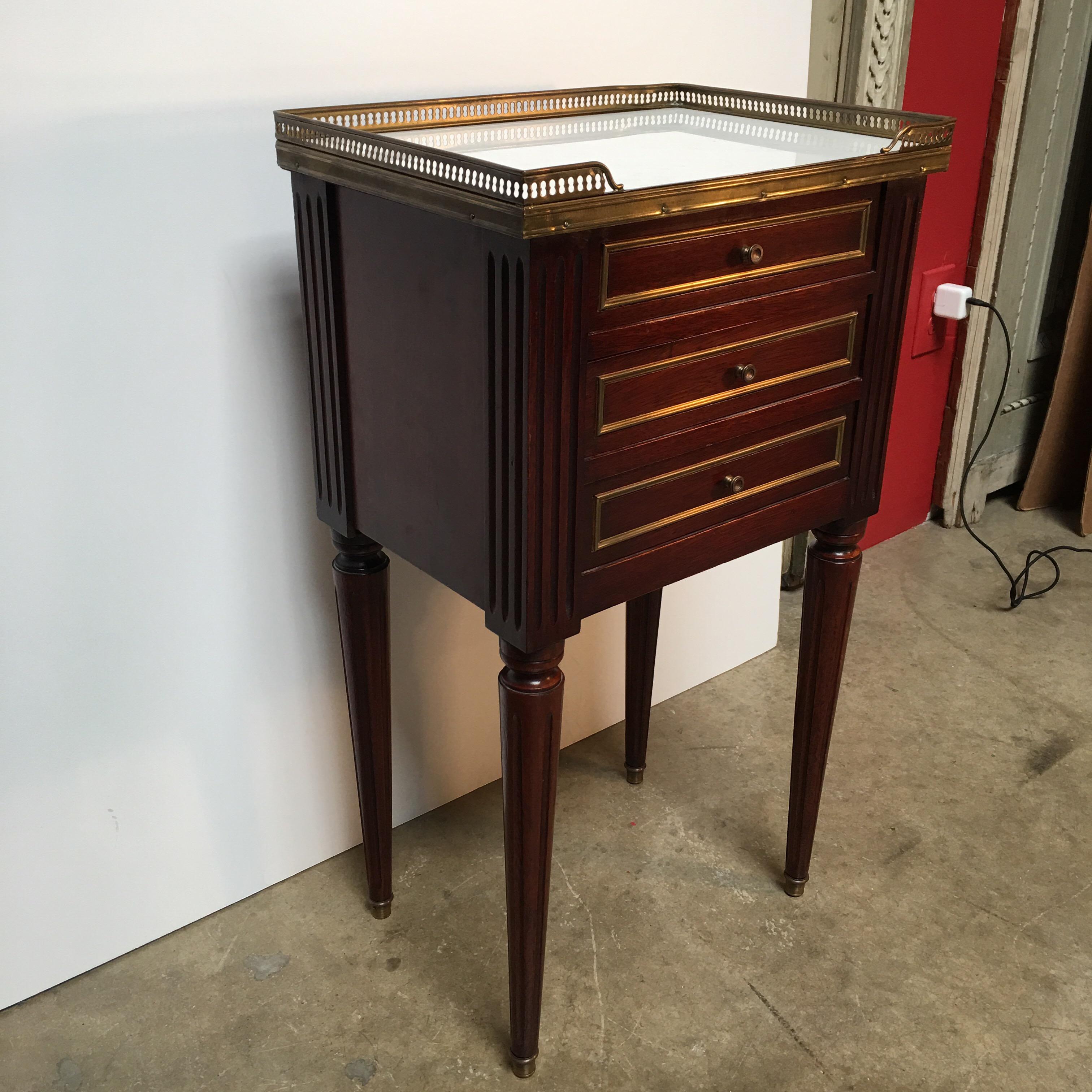 A French Louis XVI style mahogany table with gallery, drawers and a white marble top.