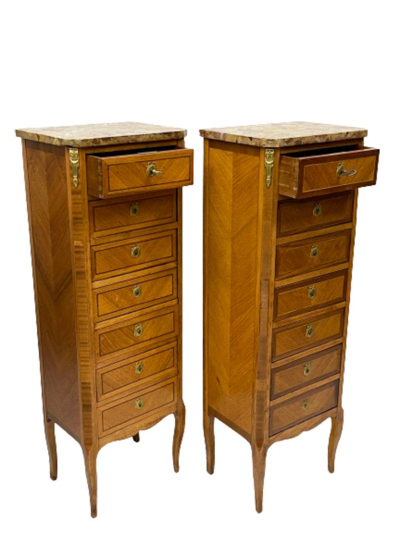 A French Louis XVI style marble top and bronze Semainiers

Rosewood chests of drawers with 7 drawers and bronze fittings on the drawers and corners. 
France, ca. 1900, 2 keys present. 
The 2 chests are similar, each has a slightly different