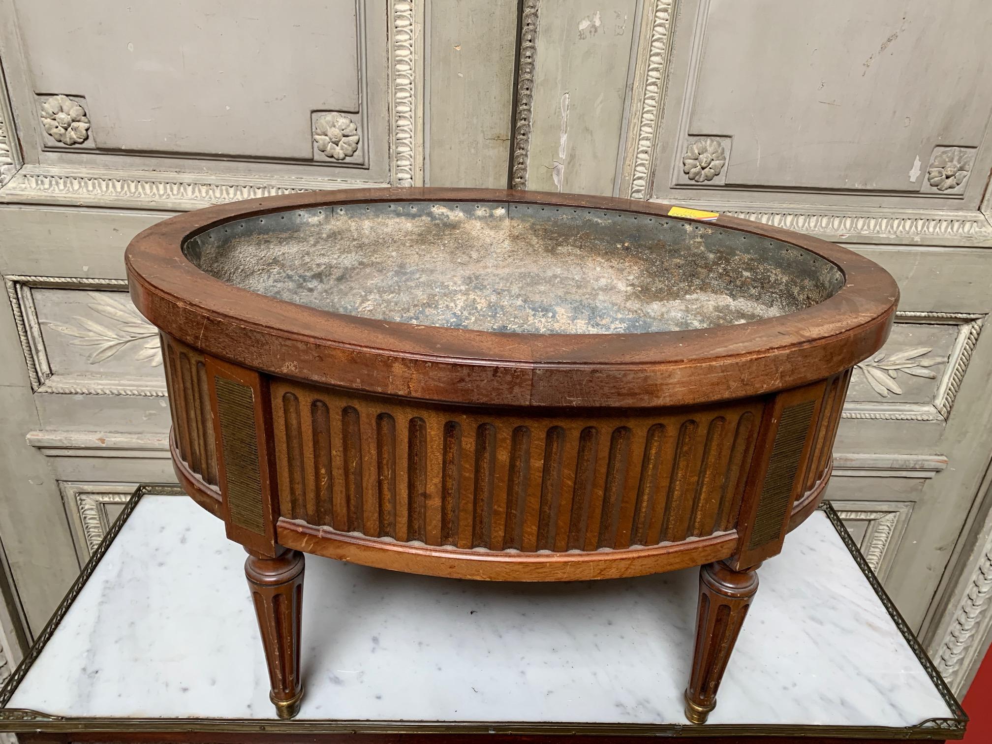 A French 19th Century Mahogany and Brass Louis XVI Style Oval Jardinière with tin-line interior. The wood jardiniere or planter is accented with fluted motif and elegant patinated brass details. 