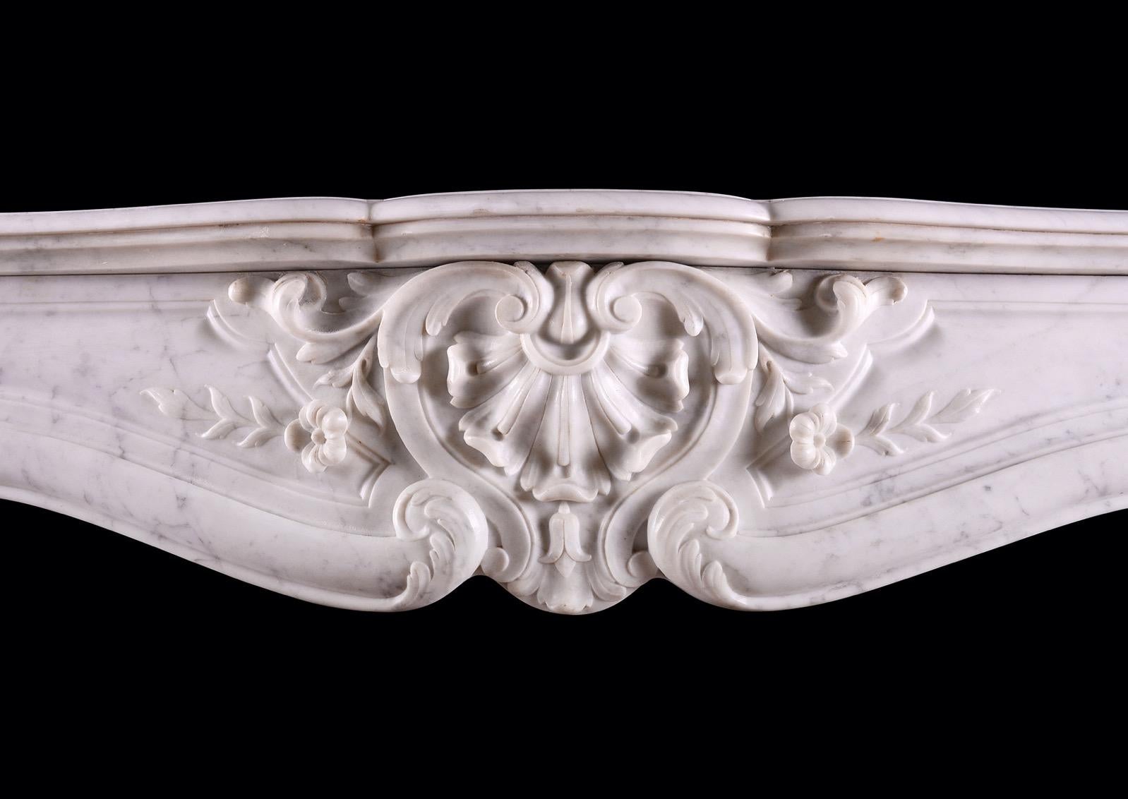 A 19th century French marble fireplace in the Louis XV style. The panelled frieze with shell to carved centre, flanked by flowers and foliage. The carved jambs with stiff acanthus leaves to base, surmounted by shaped legs and end blockings above