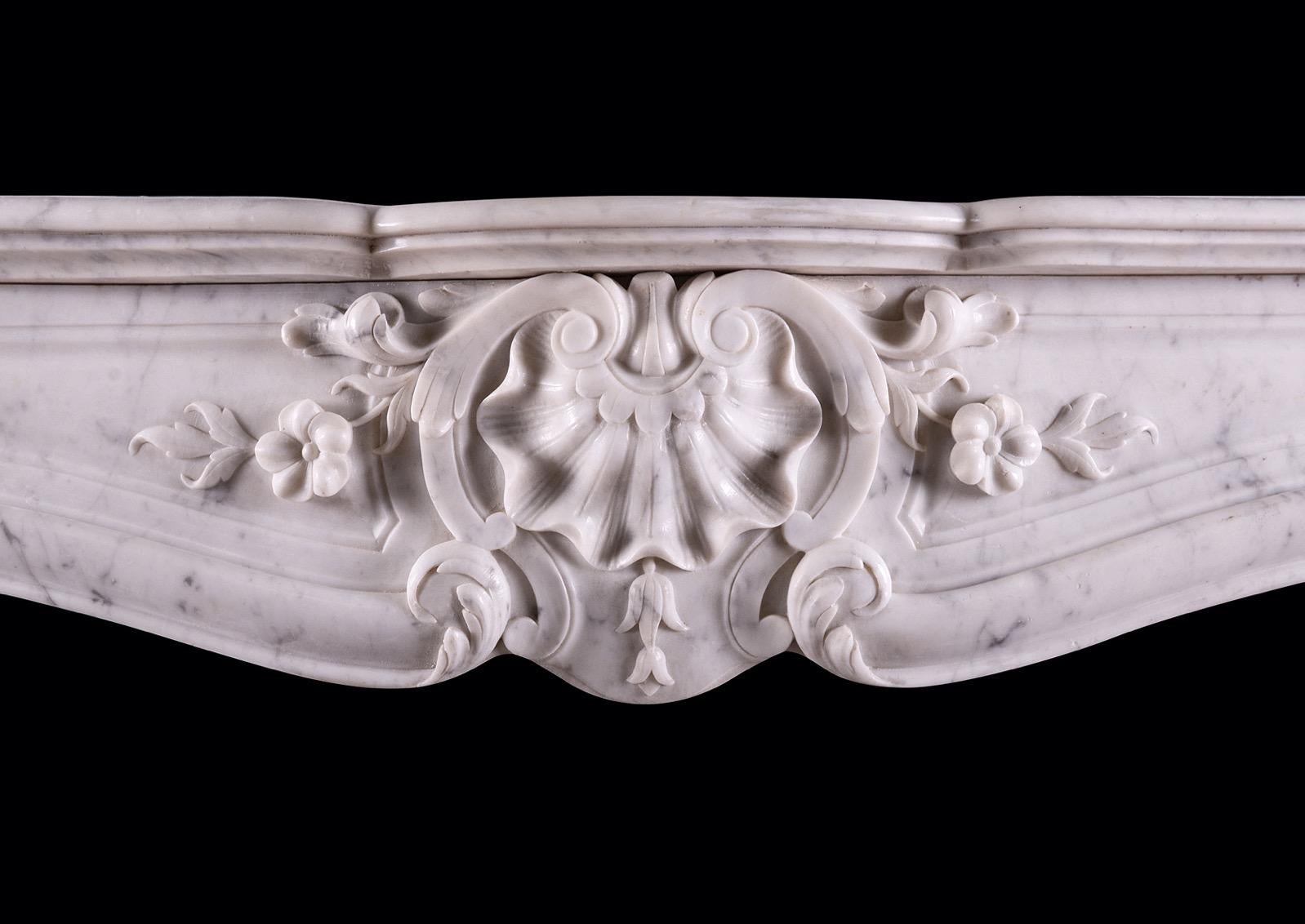 A 19th century French marble fireplace in the Louis XV style. The panelled frieze with shell to carved centre, with scrollwork throughout, the carved jambs with stiff acanthus leaves to base, surmounted by shaped legs and end blockings above carved