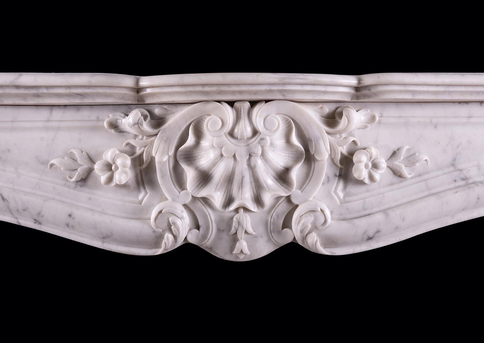 Cheminée française en marbre du XIXe siècle de style Louis XV. La frise à panneaux avec une coquille au centre sculpté, avec des volutes partout, les montants sculptés avec des feuilles d'acanthe raides à la base, surmontés de pieds façonnés et de