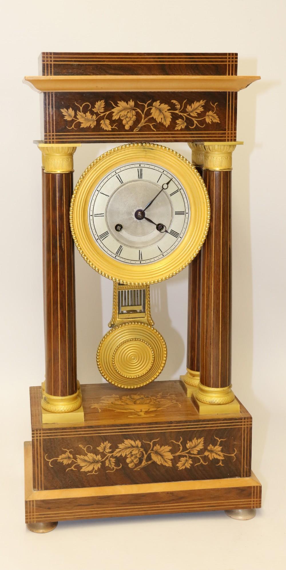 This fine example of a French Portico clock is top quality and made circa 1830.
It has a 14 day movement striking on the hour and half hour on a delicate sounding bell.
The pendulum hangs off an early silk suspension. The movement is in good