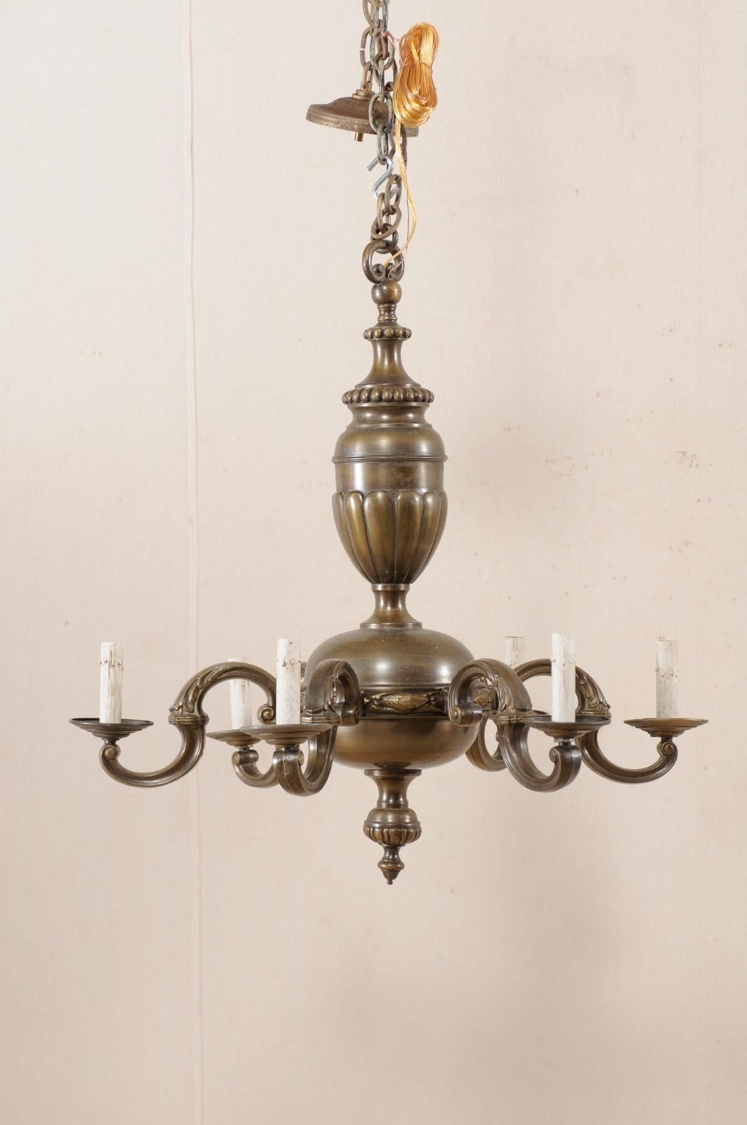 A French bronze chandelier with six lights from the mid-20th century. This vintage chandelier from France features a dark, nicely patinated bronze body. The central gallery is made up of two rounded sections, the upper more oblong, with fan and dot