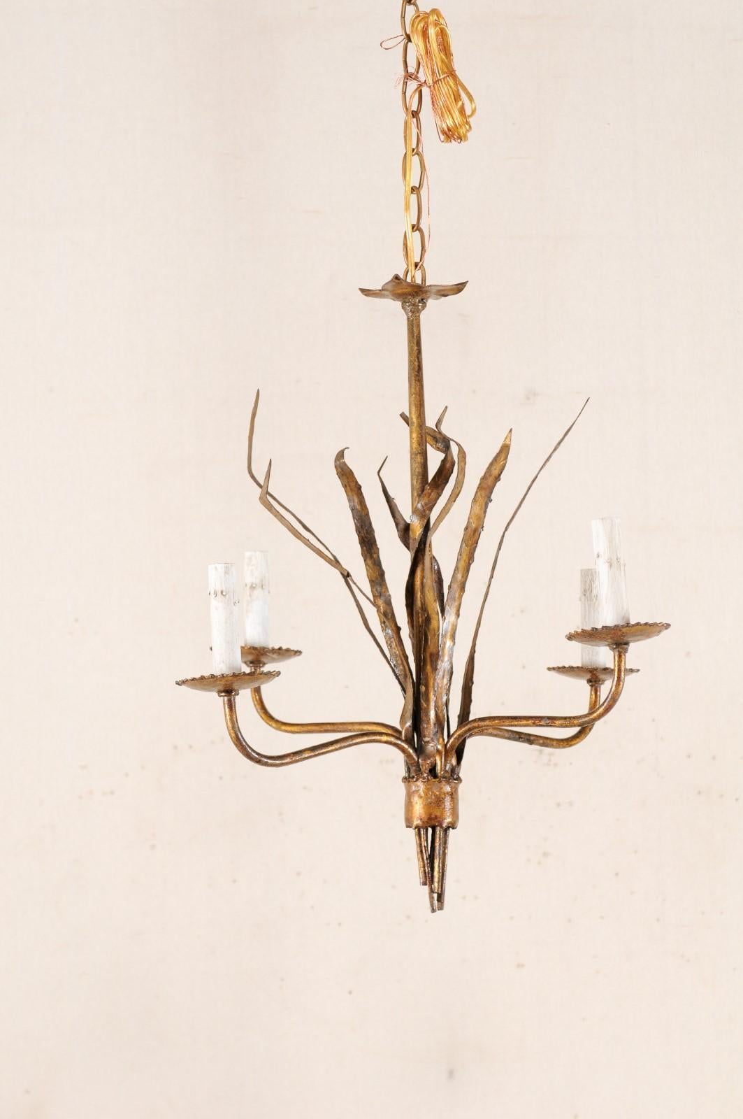 A French antiqued gold tone chandelier in foliage motif from the mid-20th century. This vintage chandelier from France features a central column surrounded within a bundled iron long-leaf fascicle motif, with a banding accent at bottom. Each of the