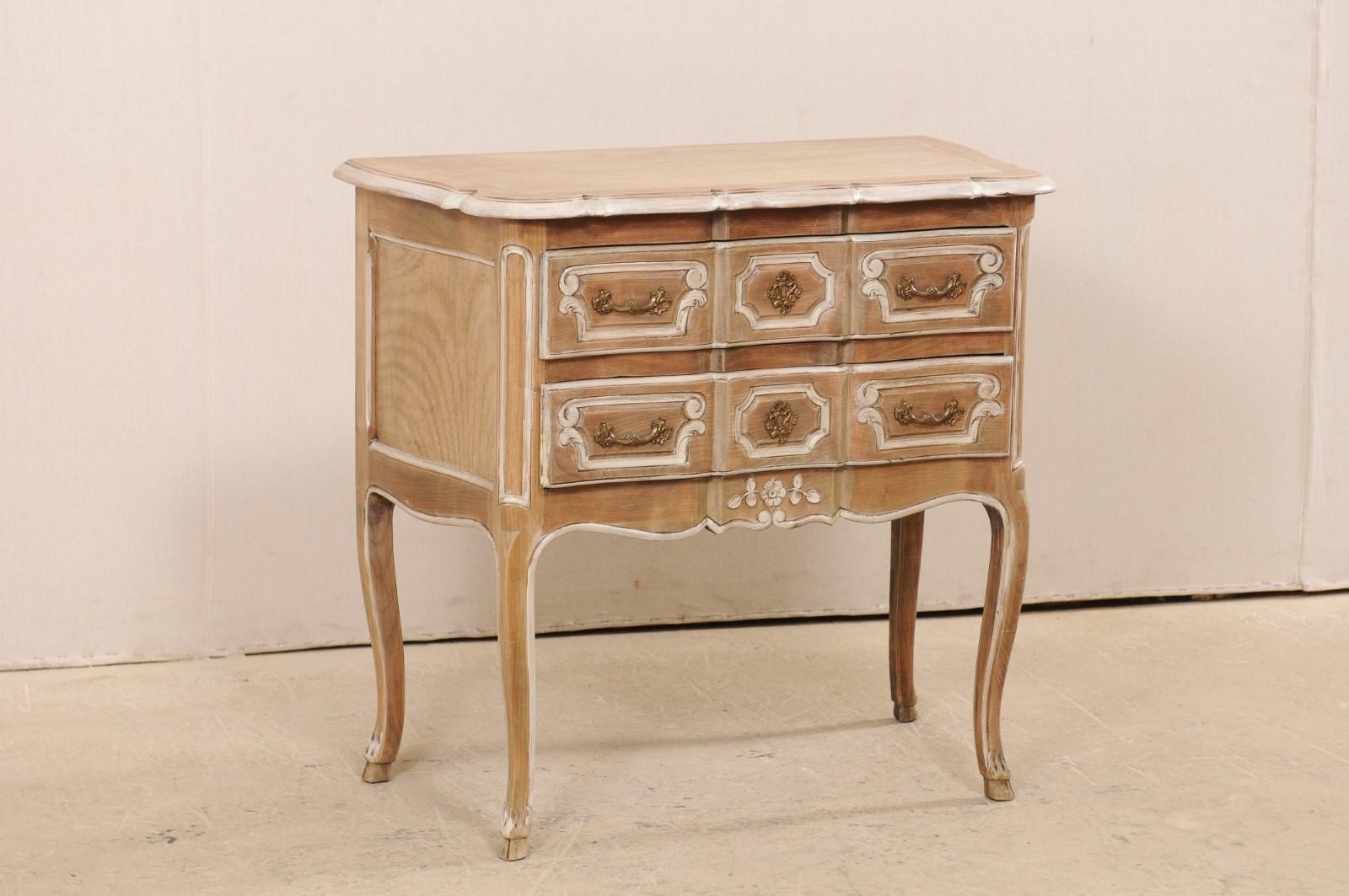 A French two-drawer raised chest from the mid -20th century. This vintage bleached wood chest from France features a beautifully scallop designed top edge (which is flat at backside), which rests atop a case housing two drawers, flanked between