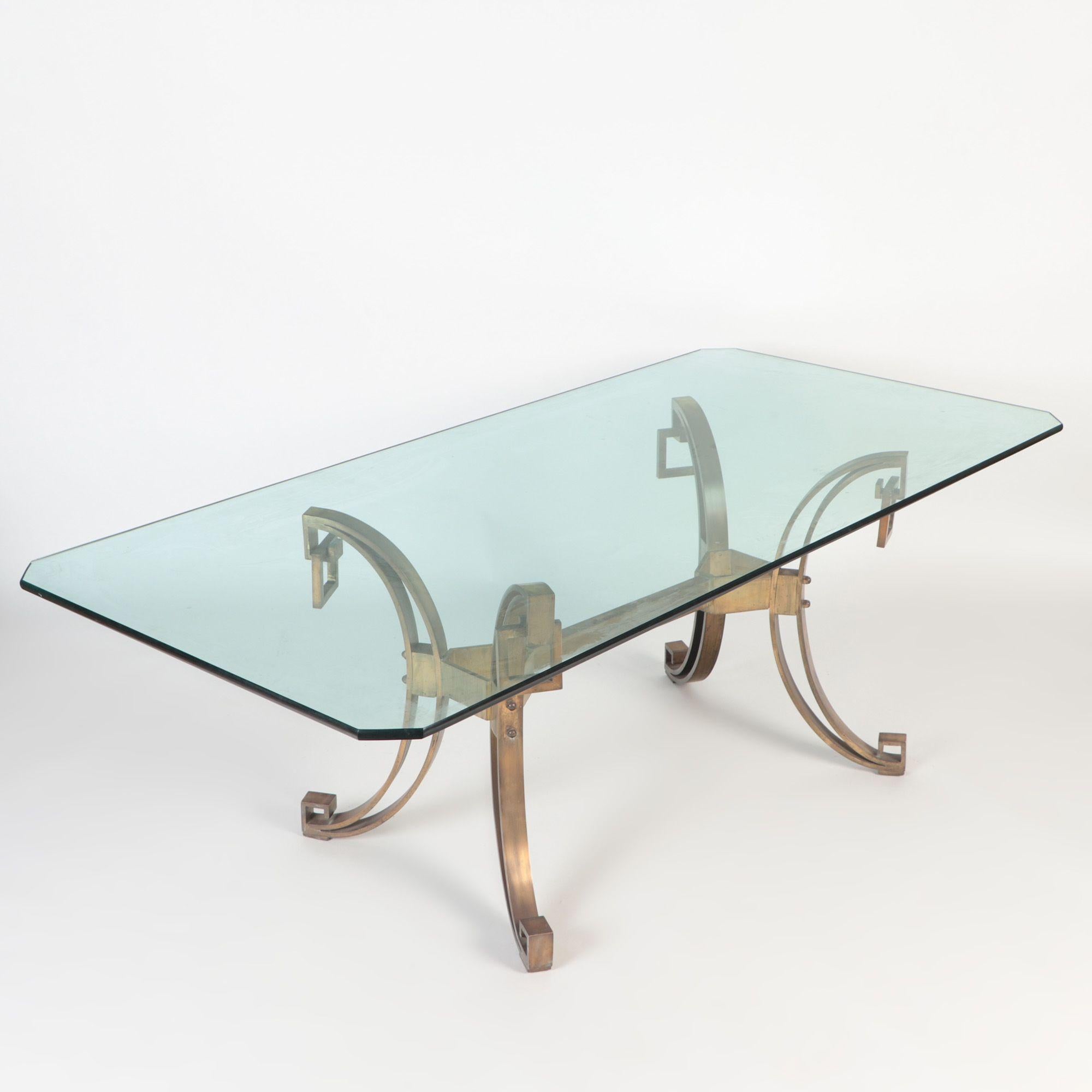 A French Modern Solid bronze dining table having a glass top, in the manner of Ramsay C 1940. The bronze bas top has four decorative rings and legs are turned inward in the form of Greek keys. Table was found in Buenos Aires, Argentina.