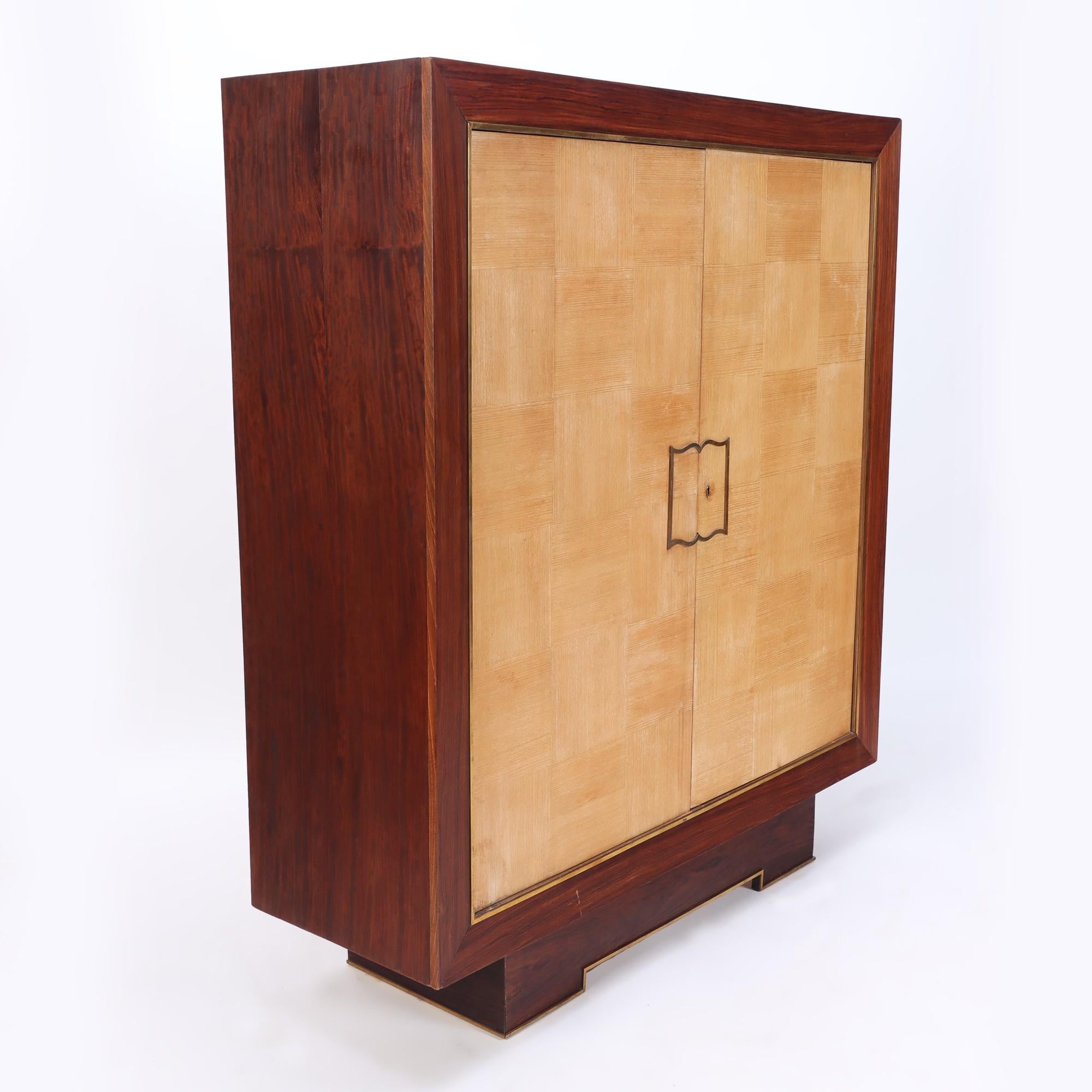 A two door cabinet with gold/bronze accents designed by Jean Royère for Gouffé. C 1935