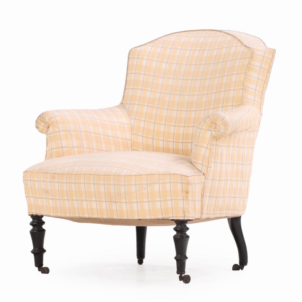 This 19th century chair was constructed with an arched crest,  slightly flaring and rolled arms, and ebonized turned front feet and flaring back feet, all terminating in brass casters. A perfect place to relax, read and recoup from a long day.