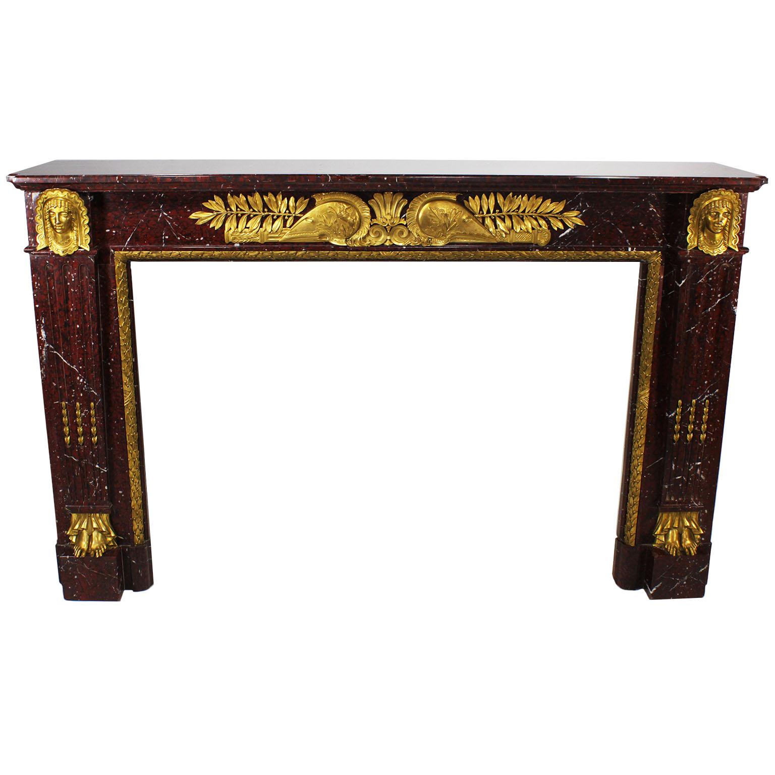 Important French Napoleon III carved Rouge Griotte Marble and ormolu mounted figural fireplace mantel chimneypiece. The rectangular carved marble body surmounted with ormolu mounts of masks of maidens above wreaths and their bare feet, with a floral