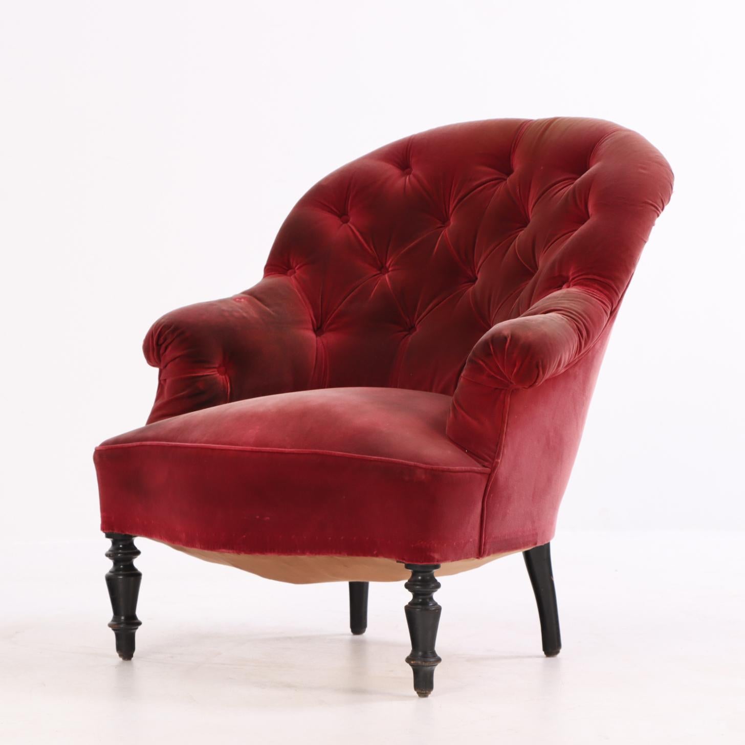 Elegant fauteuil de salon doté d'un rembourrage touffeté à boutons, d'une crête arrondie et d'accoudoirs légèrement évasés. Soutenue par des pieds tournés, cette pièce illustre le confort raffiné et l'artisanat décoratif caractéristiques de la