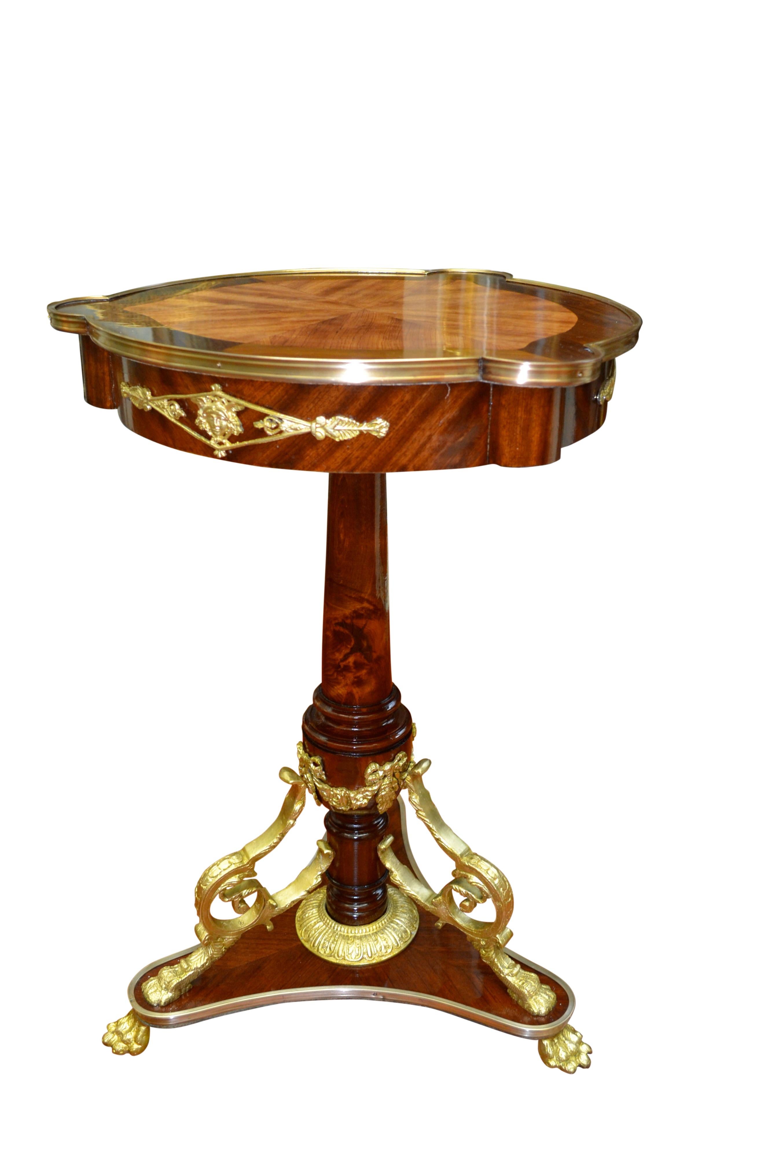 A round decorative French Napoleon III occasional pedestal table in mahogany with an inlaid tulipwood and mahogany bordered top with gilt bronze banding. The apron has decorative gilded bronze Empire style mounts to three sides. The top rests on a