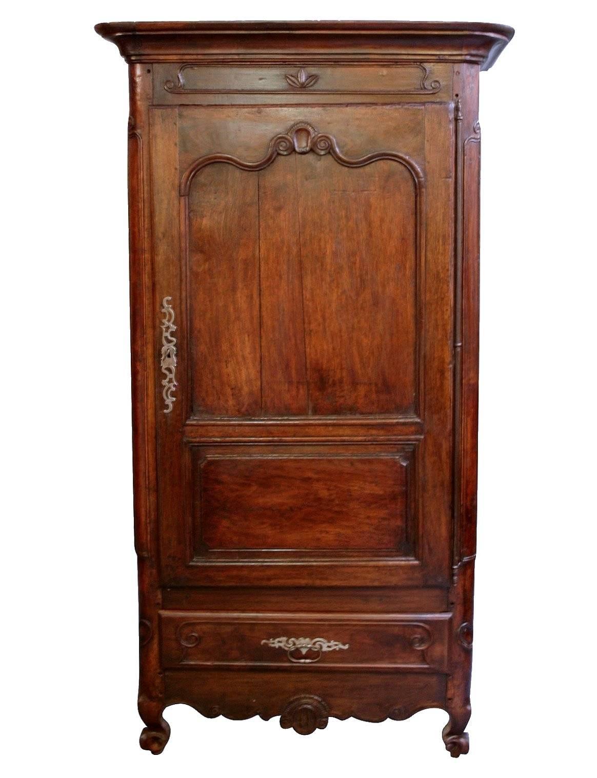 A French carved walnut armoire of narrow proportions, with central hanging space and drawer beneath.

   