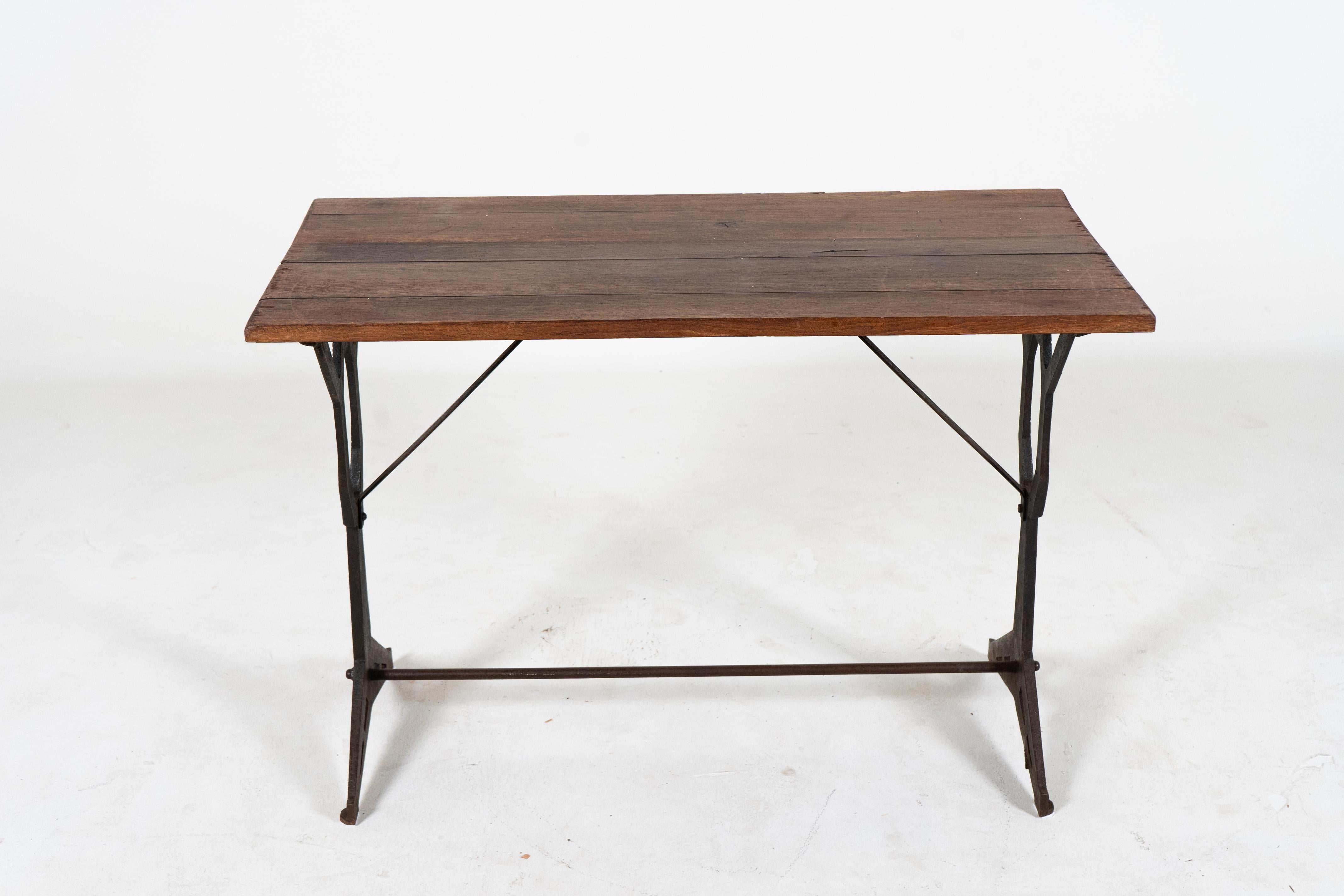 A charming vintage French bistro table from Paris with a thick rectangular slated oak wood top. This table has detailed cast iron legs with an x-shaped brace between the legs for support. The design of the legs is cubist -quite angular and unusual.