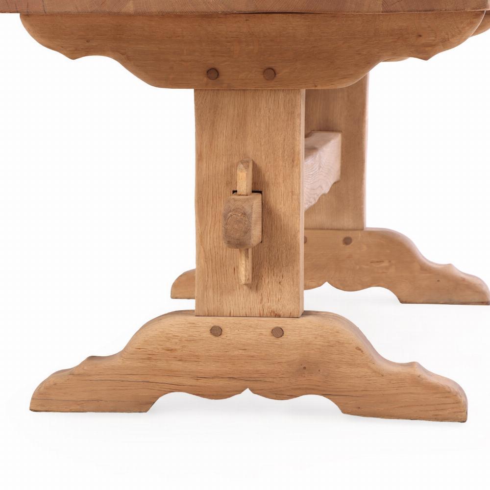 This French provincial style farmhouse dining or harvest table has a thick solid oak top which is supported by a trestle base. The hour glass shaped legs are joined by a long stretcher and terminate in wide, shaped shoe feet. 

The table was