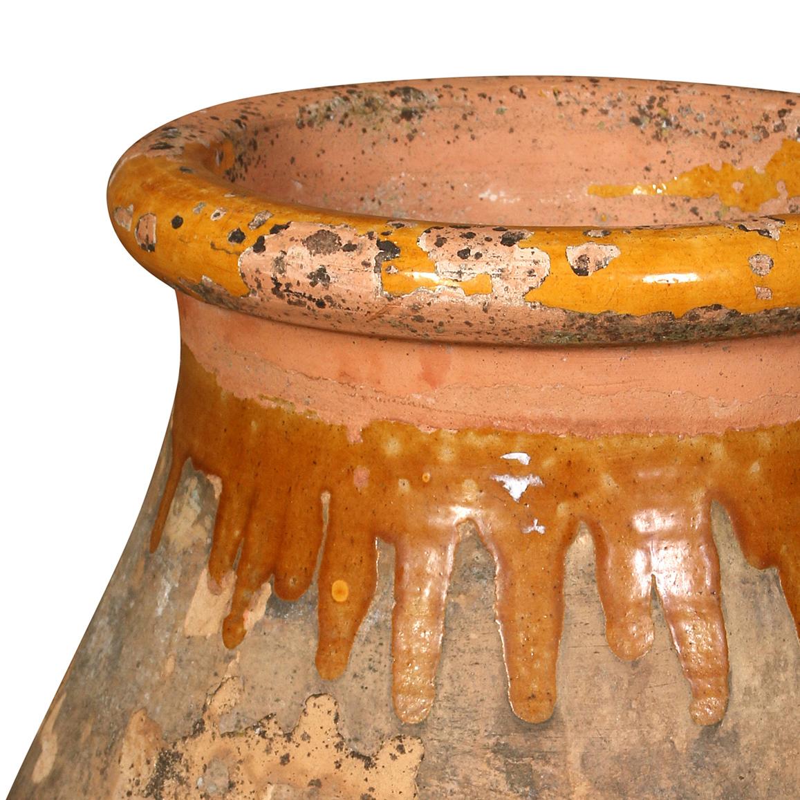 A terracotta olive jar with a wonderful mustard yellow glaze dripping from the top.  This piece has stood the test of time and has acquired a wonderfully aged patina.  It can stand alone as a decorative objet or can serve as a planter or even an