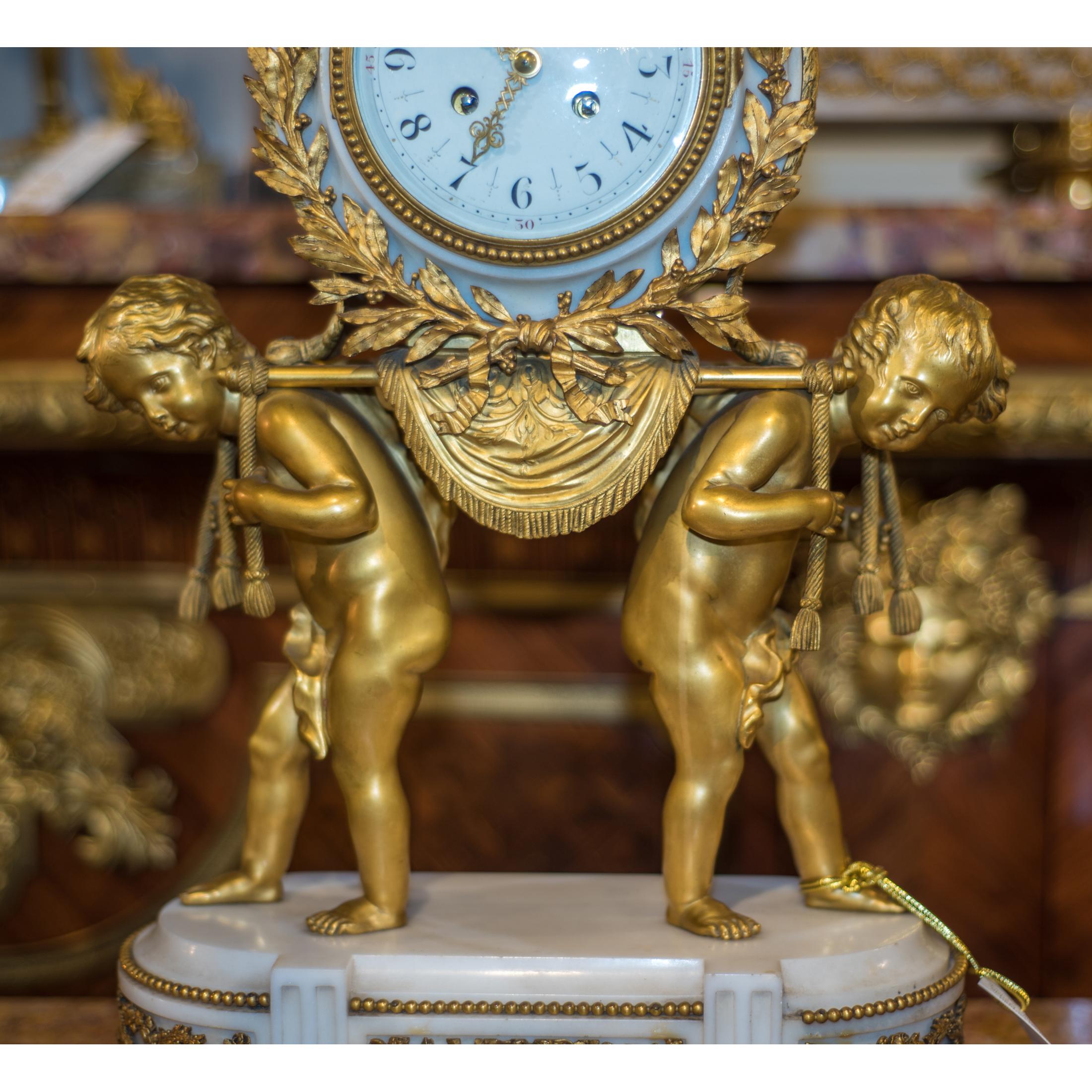 A very fine french ormolu and white marble three-piece clock set garniture. Comprising a mantel clock and a pair of matching urns with a pair of putti on an oval white marble base.

Origin: French
Date: circa 1890
Dimension: Clock 23 x 13 1/2 x