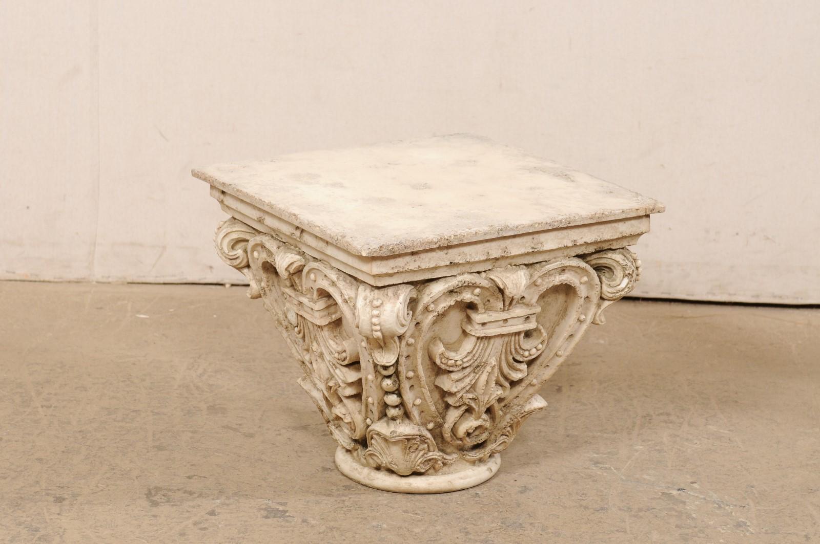 A French ornately designed small pedestal table. This vintage pedestal from France, (likely made of resin and quite heavy!) has a flat and square-shaped top which resembles a slab of stone, over a heavily detailed base comprised of leafy scrolls,