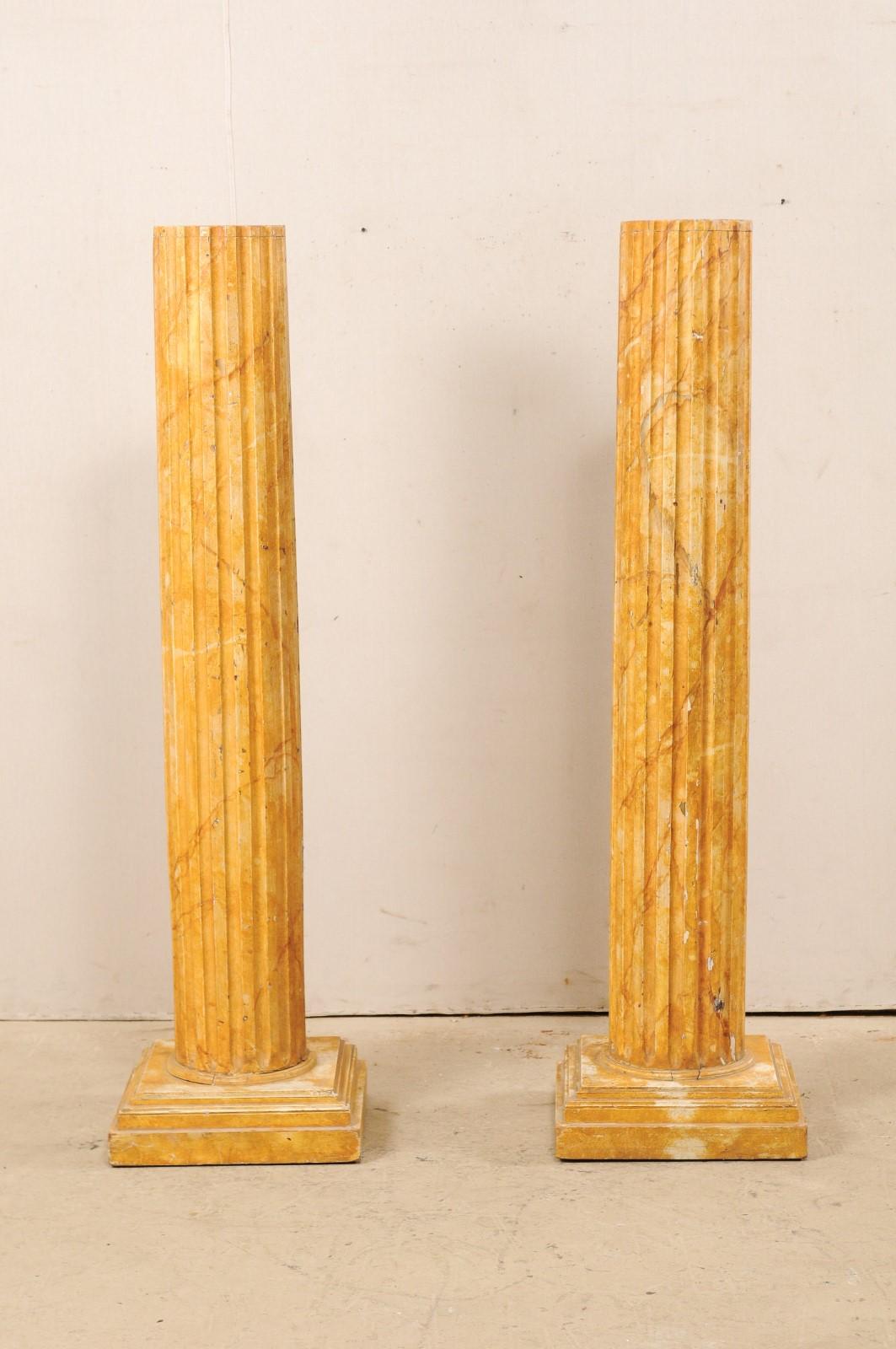 Ein Paar französische kannelierte Holzsäulen mit falscher Marmorierung aus der Mitte des 20. Jahrhunderts. Diese Vintage-Säulen aus Frankreich haben runde, kannelierte Schäfte mit flacher Spitze und stehen auf gestapelten quadratischen Sockeln. Die