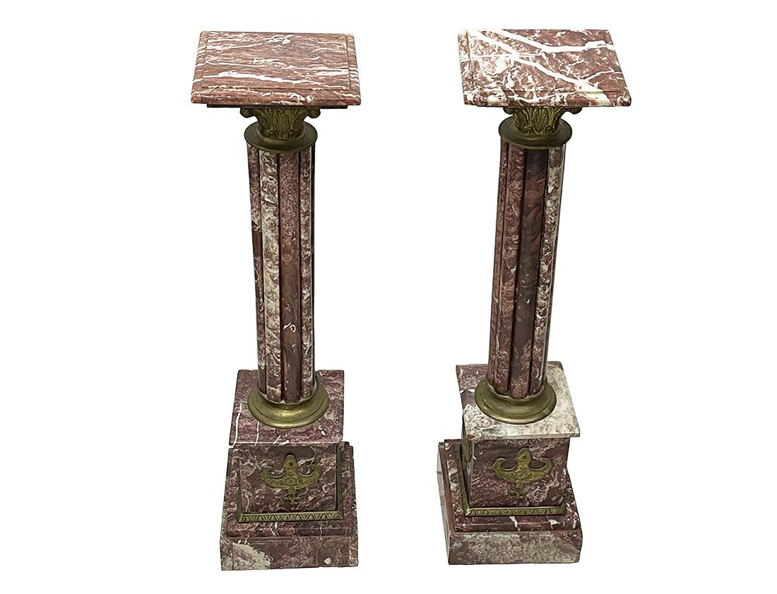 A French pair of marble columns pedestals, ca 1900

A pair of marble columns with plateau in bordeaux and white color marble stone with several round vertical bars of marble on a square marble base. Decorated with brass. 
The measurement is 103 cm