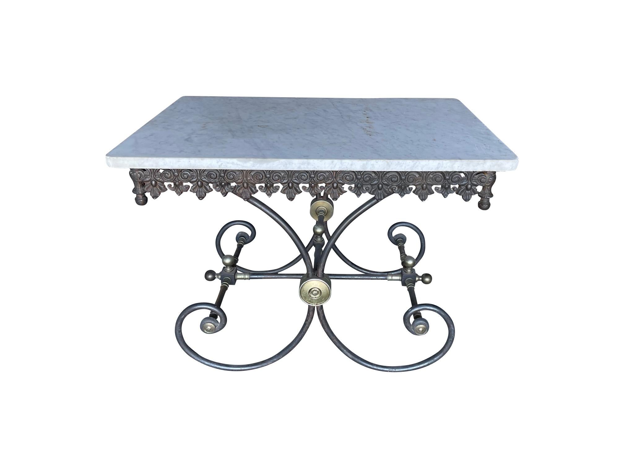 A French Patisserie table with an iron foliate frieze, scrolling iron base with decorative brass finials and a thick marble top

This table would work well as a console table in a hallway, it is an unusual piece that would enhance any interior