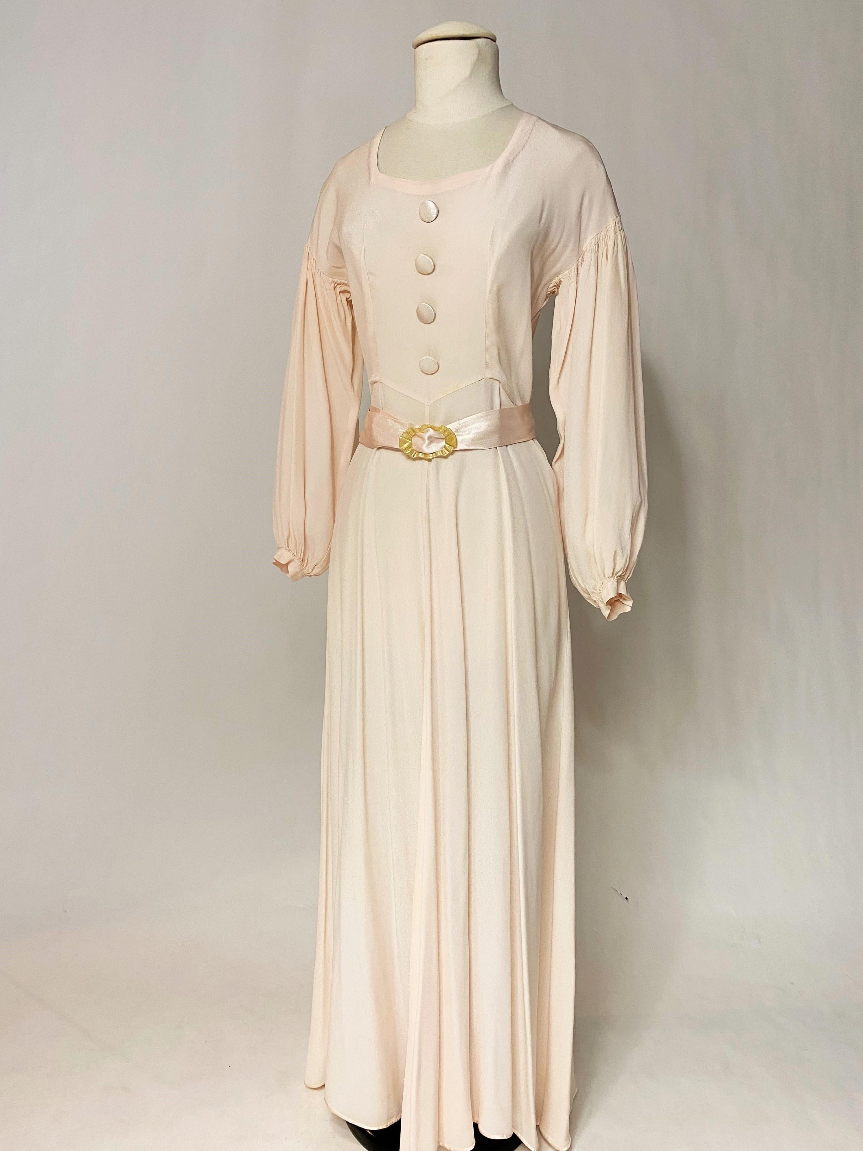 Circa 1940
France

A Collectible Long dress for evening or ceremony in Fibrane, a reversible matte and satin crepe in artificial fibre, in a subtle powder pink colour, dating from the 1940s. Long puffed sleeves with fine shoulder pleats, square