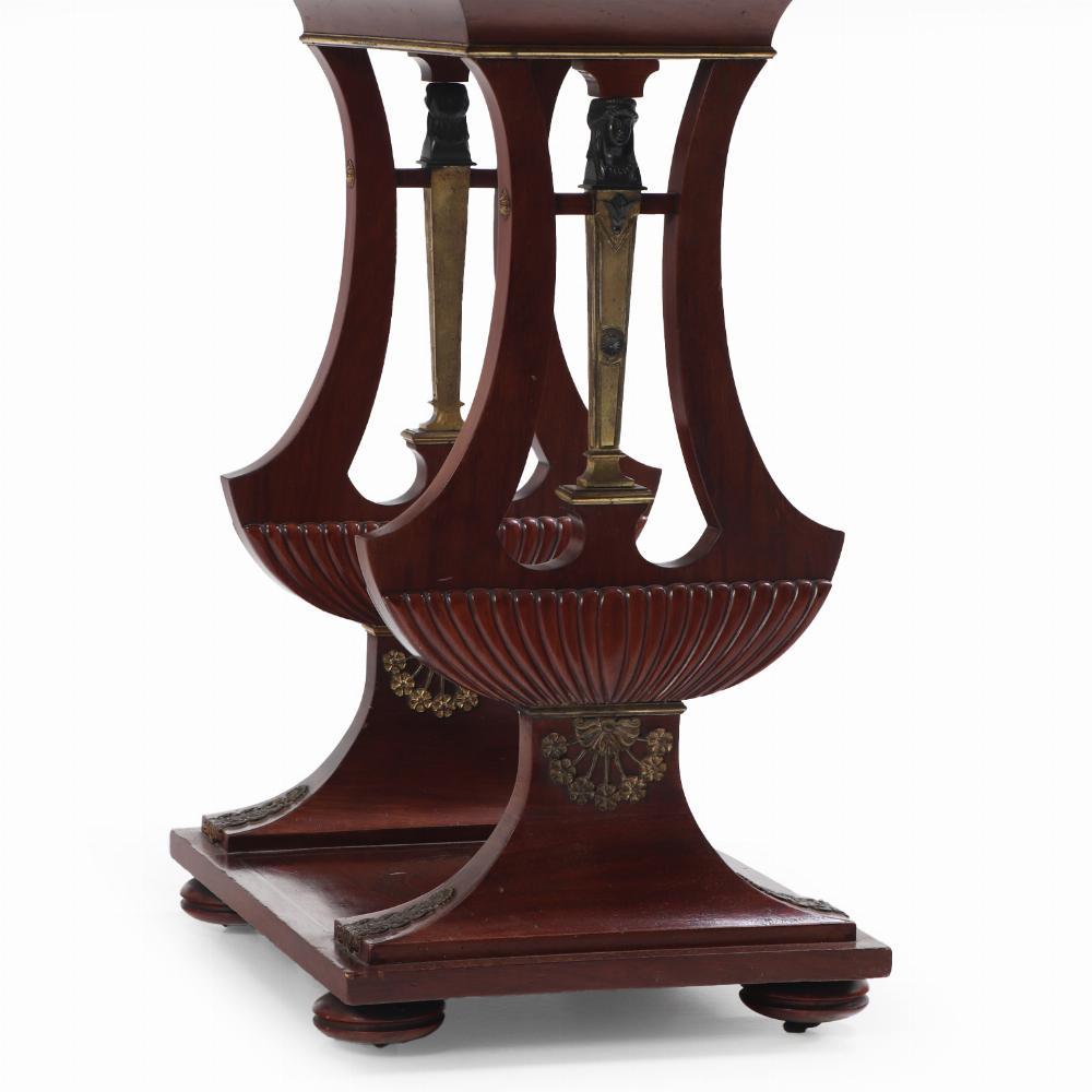 This decorative side table has a band of bronze inlay around the perimeter of the top which sits on double lyre form supports with figural bronze mounts, all on a rectangular base raised on small circular feet.