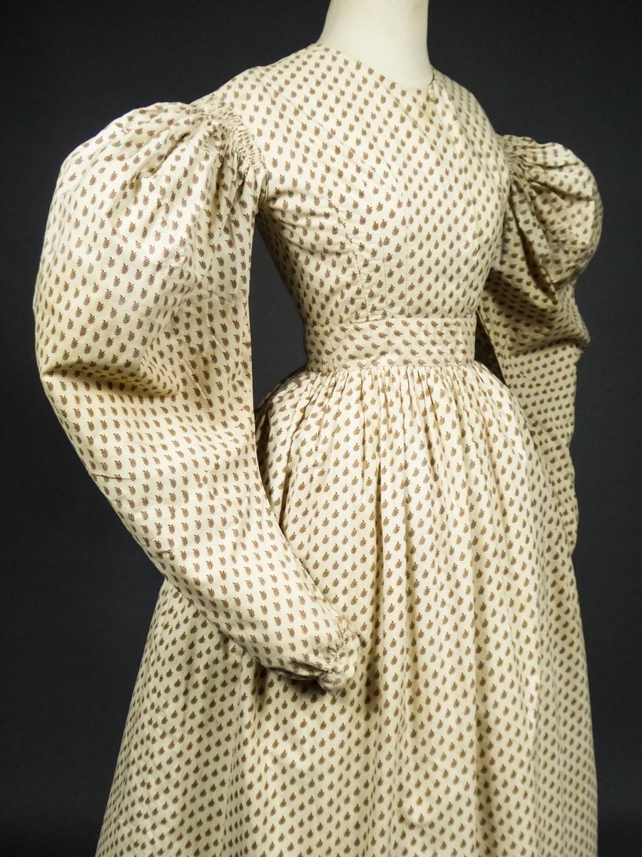 Circa 1830
France Louis-Philippe Period

Printed roller walking or afternoon cotton day dress with a pattern of small light brown ribbed leaves. Very fitted bodice with a crew neck and oversized mutton sleeves, finely pleated and piped at the