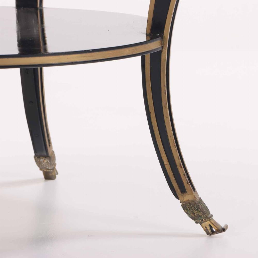 This elegant, ebonized table, with its gently curving legs and gilt details will be a wonderful addition to more formal interiors. The marble top is encircled by a bronze banded edge with lion's mask embellishments, above a lower tier joining the