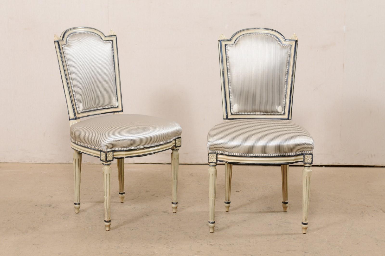 Un ensemble français de quatre chaises d'appoint en bois sculpté et rembourré du milieu du 20e siècle. Cet ensemble de chaises vintage de France a un dossier encadré en bois sculpté, avec des rails supérieurs arqués larges et allongés et des épis de