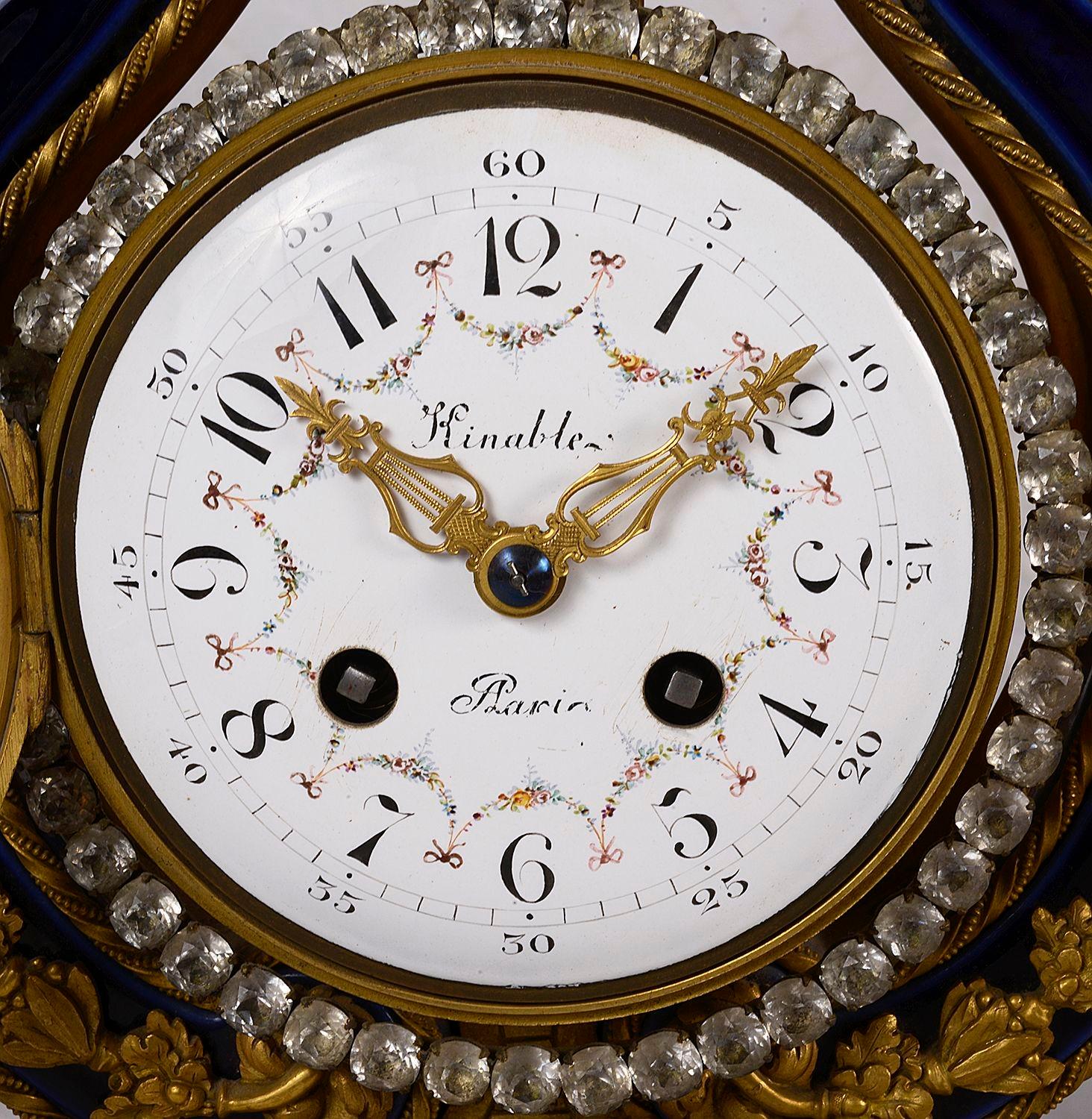 A French Sevres style cobalt blue lyre clock with finely cast ormolu sunburst and floral swagged mounts with jewelled bezel, pretty floral swag painted enamlled dial and finely pierced hands. Having an eight day duration and striking on hour and