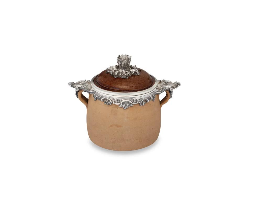 A French silver mounted two-handled earthenware soup crock pot.

MARK OF BOIN-TABURET, PARIS, CIRCA 1890

Of brown earthenware, mounted with leafy rocaille rim and boldly cast leaf-capped small loop handles, the slightly domed cover with silver