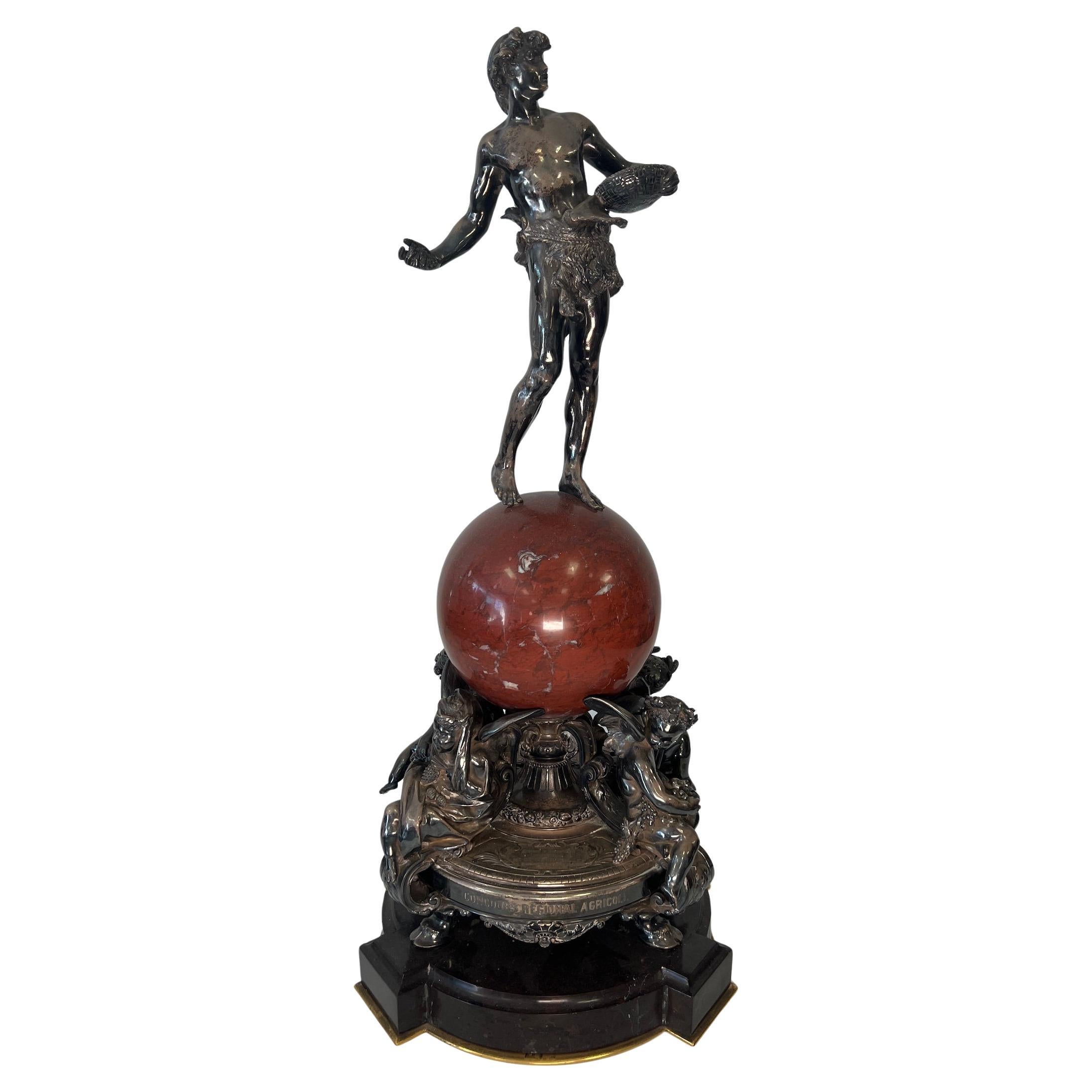 Trophée de présentation en argent et marbre rouge
Par Christofle & Cie, Paris, daté de 1885
Le globe en marbre rouge est surmonté d'une figure de semeur, soutenue par quatre putti ailés emblématiques des Quatre Saisons, sur un support circulaire