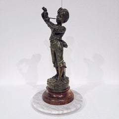 A spelter french  statue of a boy lighting a pipe, by Delavigne
