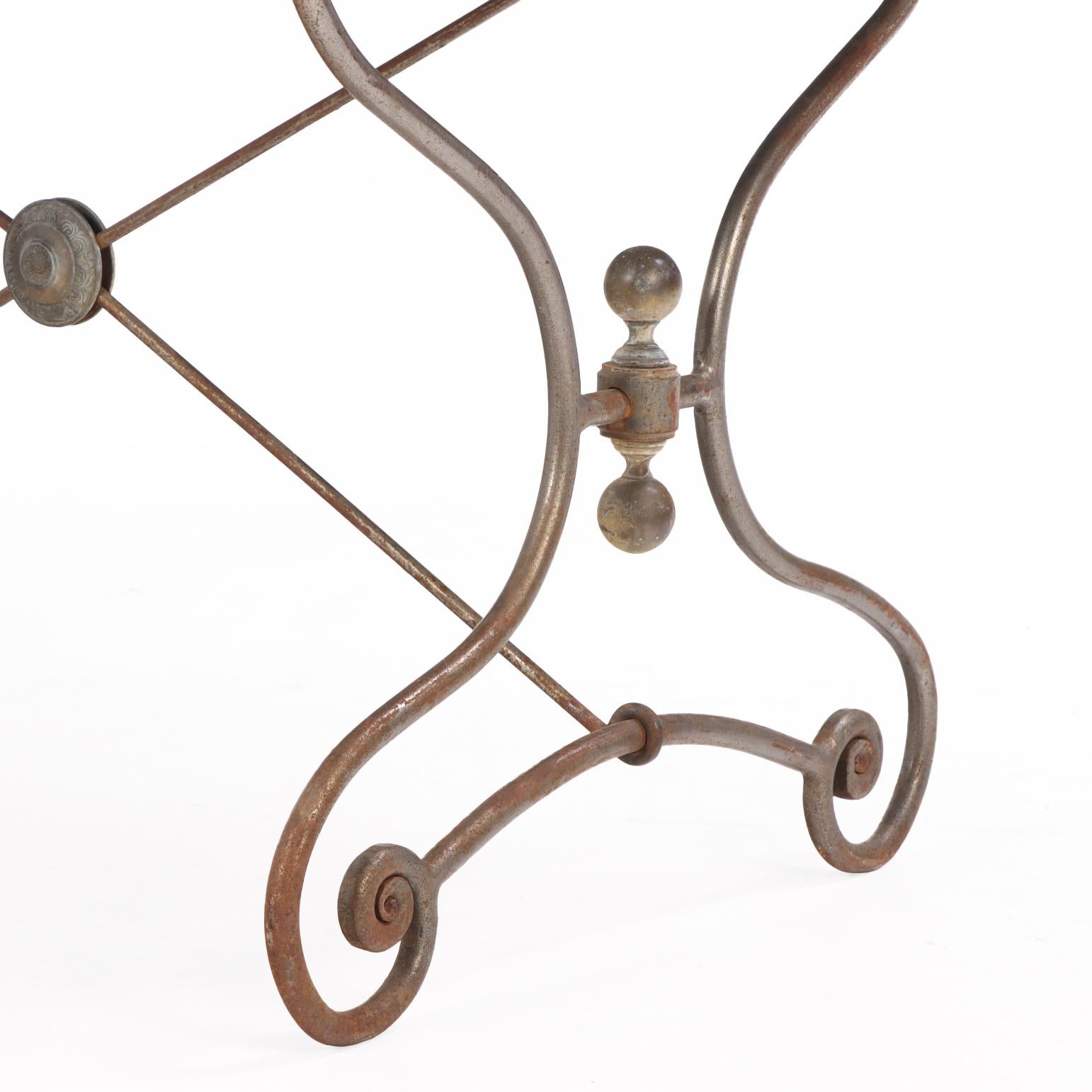 Une table française polyvalente pour les repas sur le patio ou dans le jardin, qui peut également servir de table console. Surmontée d'une solide dalle de pierre bleue, la base métallique à volutes assure la stabilité structurelle tandis que la