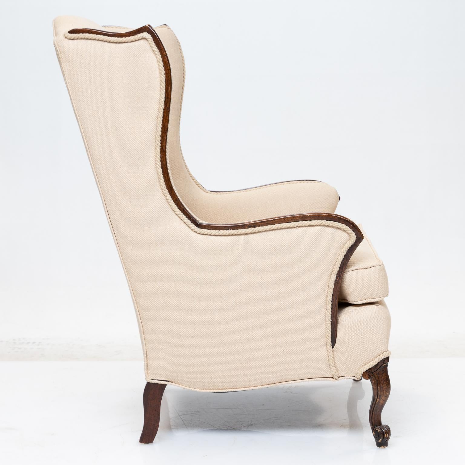 A French style wing chair. Upholstered with a heavy with a cream fabric. Mahogany wood. Fantastic shaping in the design of this chair. Vintage chair from the 1950s has been re-upholstered recently. Very nice quality chair.