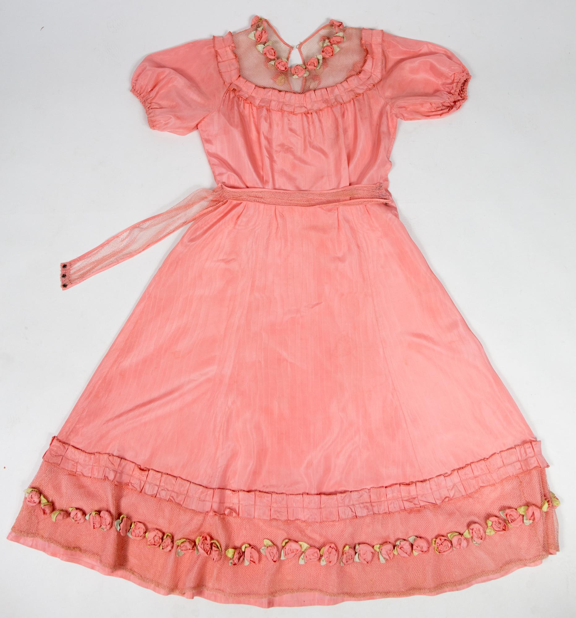 Circa 1920/1930

France

Pretty summer dress in pink rayon decorated with roses dating from the years 1920/1930. Pleated bustier with small puffed sleeves and bateau neckline with cotton mesh neckline adorned with roses. Falbalas pleated in pink